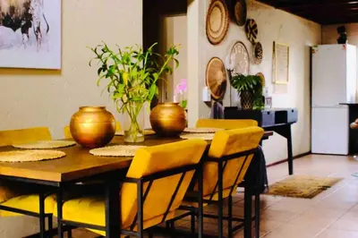 a dining room with a table and yellow chairs at Perfectly located beauty in secure Estate in Sandton