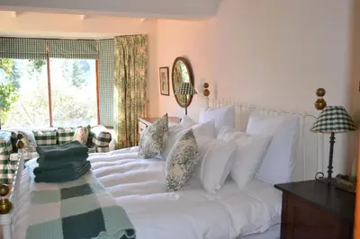 a bedroom with a white bed with pillows and a window at Dullies Cottage in Dullstroom
