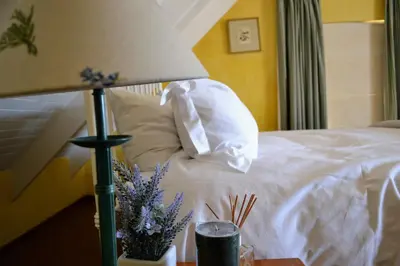 a bed with a white pillow and a lamp on a table at Dullies Cottage in Dullstroom
