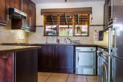a kitchen with wooden cabinets and a dishwasher at Kruger Park Lodge Unit No 521 with Private Pool in Hazyview