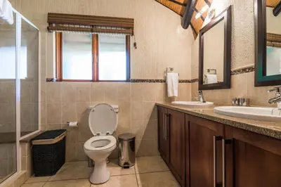 a bathroom with a toilet and a sink and a mirror at Kruger Park Lodge Unit No 521 with Private Pool in Hazyview