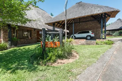 a house with a thatched roof and a car parked in front at Kruger Park Lodge Unit No 521 with Private Pool in Hazyview