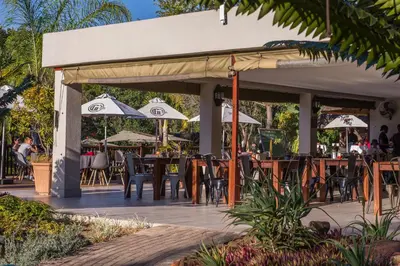 a patio with tables and chairs and umbrellas at Kruger Park Lodge Unit No 521 with Private Pool in Hazyview