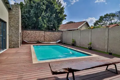 a swimming pool on a wooden deck next to a fence at House of Bongekile 4 Bed Luxury Home in Malelane in Malelane