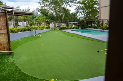 a putting green with a pool in a backyard at Peaceful gateaway - 2 bed apartment in Sunninghill with back-up power in Sandton