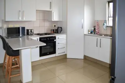 a kitchen with white cabinets and a counter top at Peaceful gateaway - 2 bed apartment in Sunninghill with back-up power in Sandton