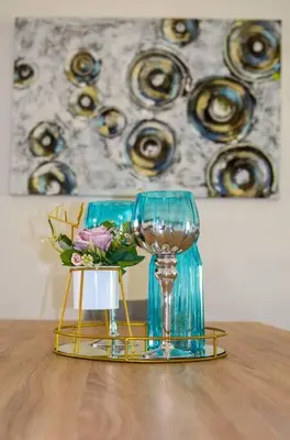 a table with a wine glass and a vase with flowers at Peaceful gateaway - 2 bed apartment in Sunninghill with back-up power in Sandton