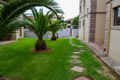 a green lawn with a palm tree in a yard at Peaceful gateaway - 2 bed apartment in Sunninghill with back-up power in Sandton
