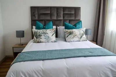 a bedroom with a large white bed with blue pillows at Peaceful gateaway - 2 bed apartment in Sunninghill with back-up power in Sandton