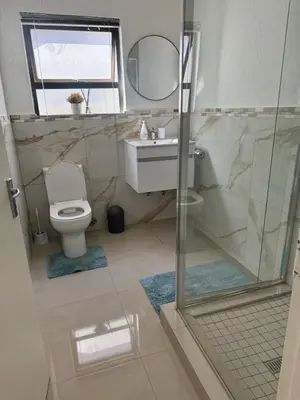 a bathroom with a shower and a toilet and a sink at Peaceful gateaway - 2 bed apartment in Sunninghill with back-up power in Sandton