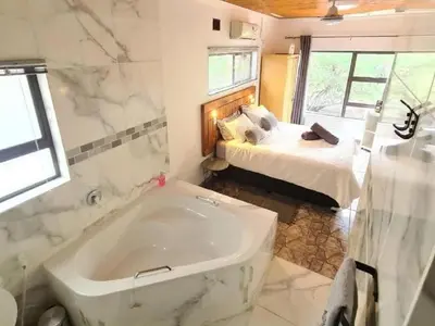 a bathroom with a tub and a bedroom with a bed at Dream Inn in Marloth Park