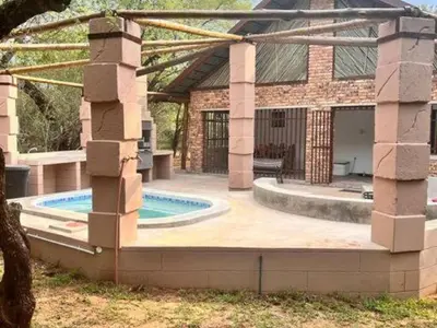 a house with a swimming pool in front of a building at Dream Inn in Marloth Park
