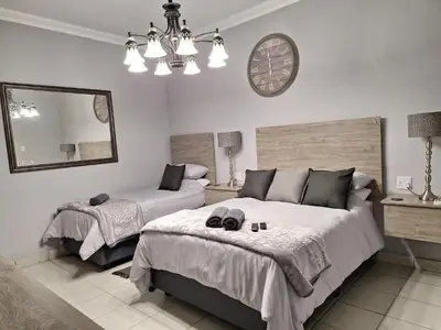a bedroom with two beds and a clock on the wall at 21on2nd Avenue in Tzaneen