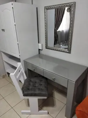 a gray desk with a mirror and a chair at 21on2nd Avenue in Tzaneen