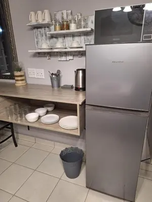 a kitchen with a refrigerator and a counter with dishes at 21on2nd Avenue in Tzaneen