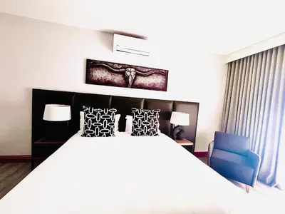 a bedroom with a large bed and a blue chair at Panorama Boutique Guest House in Graskop