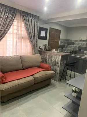 a living room with a couch and a kitchen at The Villa 442 in Pretoria