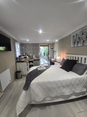 a bedroom with a large bed and a kitchen at Country Cabin in Midrand