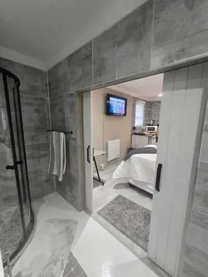 a bathroom with a shower and a bed and a television at Country Cabin in Midrand