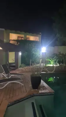 a light on a house with a swimming pool at night at Country Cabin in Midrand