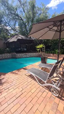 a pair of chairs and an umbrella next to a pool at Country Cabin in Midrand