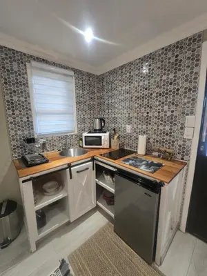 a small kitchen with a sink and a microwave at Country Cabin in Midrand