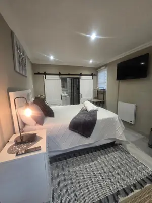 a bedroom with a large bed and a table with a lamp at Country Cabin in Midrand