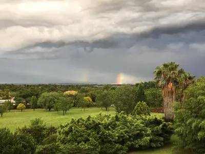 a rainbow in the sky over a field with trees at Oak Tree Lodge, Beaulieu, Kyalami in Midrand