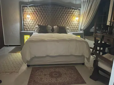 a bedroom with a large bed with a large headboard at Oak Tree Lodge, Beaulieu, Kyalami in Midrand