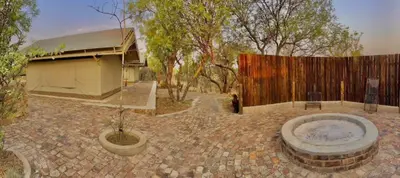 a courtyard with a fence and a building with a tree at Oryx Wilderness Game Lodge and Tented Camp in Rhenosterfontein