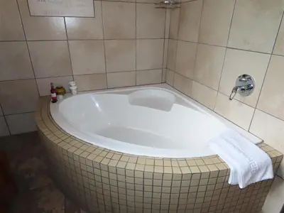 a bath tub in a bathroom with a towel at Adventure Bush House II in Marloth Park