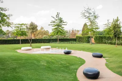 a garden with white chairs and a pond in the grass at Menlyn Maine Gem in Pretoria