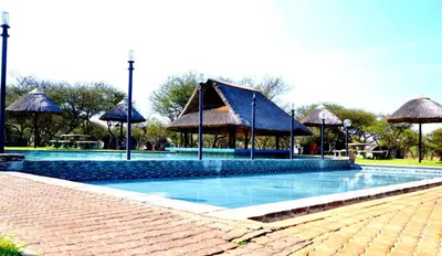 a swimming pool with a pavilion and umbrellas at Bradbury Game Lodge and Function Venue in Polokwane