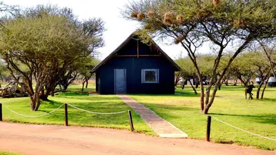 a blue house in the middle of a field with trees at Bradbury Game Lodge and Function Venue in Polokwane
