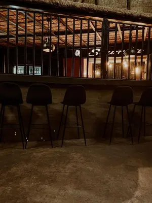 a bar with three stools sitting under a shelf at Bradbury Game Lodge and Function Venue in Polokwane