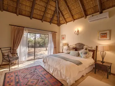 a bedroom with a bed and a large window at Luxurious 4 Bedroom Villa 94 in Mabula