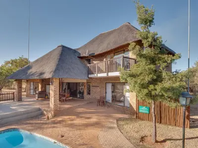 a house with a thatched roof and a pool at Luxurious 4 Bedroom Villa 94 in Mabula