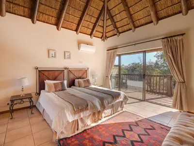 a bedroom with a large bed and a balcony at Luxurious 4 Bedroom Villa 94 in Mabula
