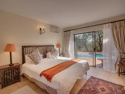 a bedroom with a large bed and a large window at Luxurious 4 Bedroom Villa 94 in Mabula
