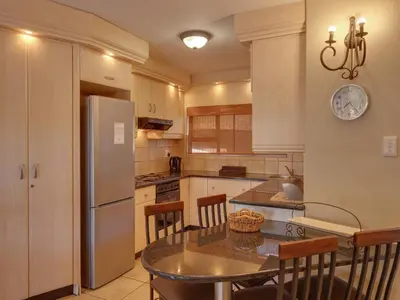 a kitchen with a table and a refrigerator at Luxurious 4 Bedroom Villa 94 in Mabula