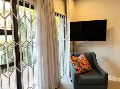 a living room with a tv and a chair and a window at The Windsor- Hartbeespoort Dam in Hartbeespoort