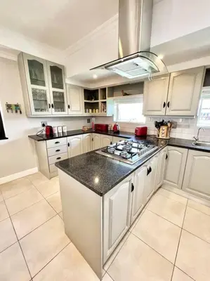 a kitchen with white cabinets and a black counter top at The Windsor- Hartbeespoort Dam in Hartbeespoort