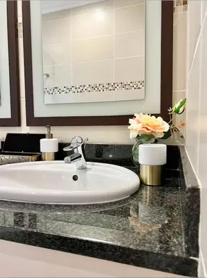 a bathroom with a sink and a mirror and flowers at The Windsor- Hartbeespoort Dam in Hartbeespoort