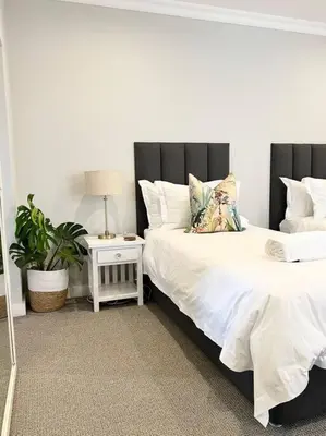 a bedroom with two beds and a table with a lamp at The Windsor- Hartbeespoort Dam in Hartbeespoort