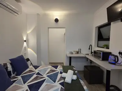 a bedroom with a bed and a desk in it at East Park Inn in Polokwane