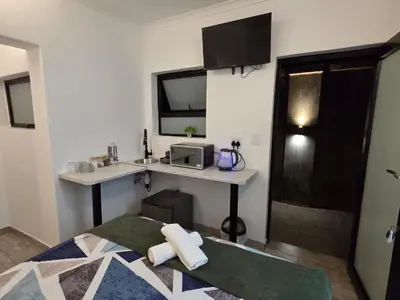 a bedroom with a bed and a desk with a microwave at East Park Inn in Polokwane