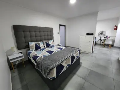 a bedroom with a large bed and a dresser at East Park Inn in Polokwane