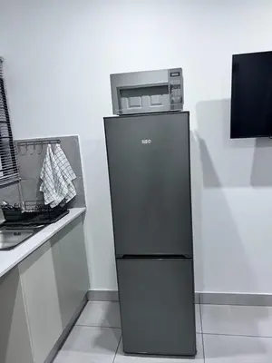 a black refrigerator with a microwave on top of it at Beevap Guesthouse in Pretoria