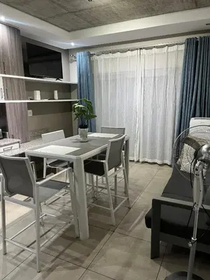 a dining room with a white table and chairs at Stunning City Living at Loftus in Pretoria