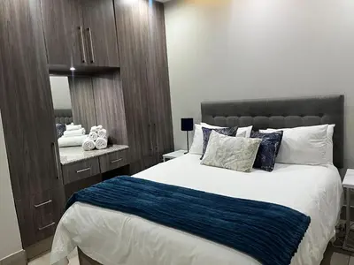 a bedroom with a large bed and a mirror at Stunning City Living at Loftus in Pretoria